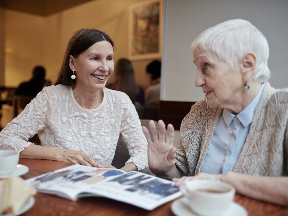 Ältere Frau, die mit einer jüngeren Frau über einem Katalog sitzt