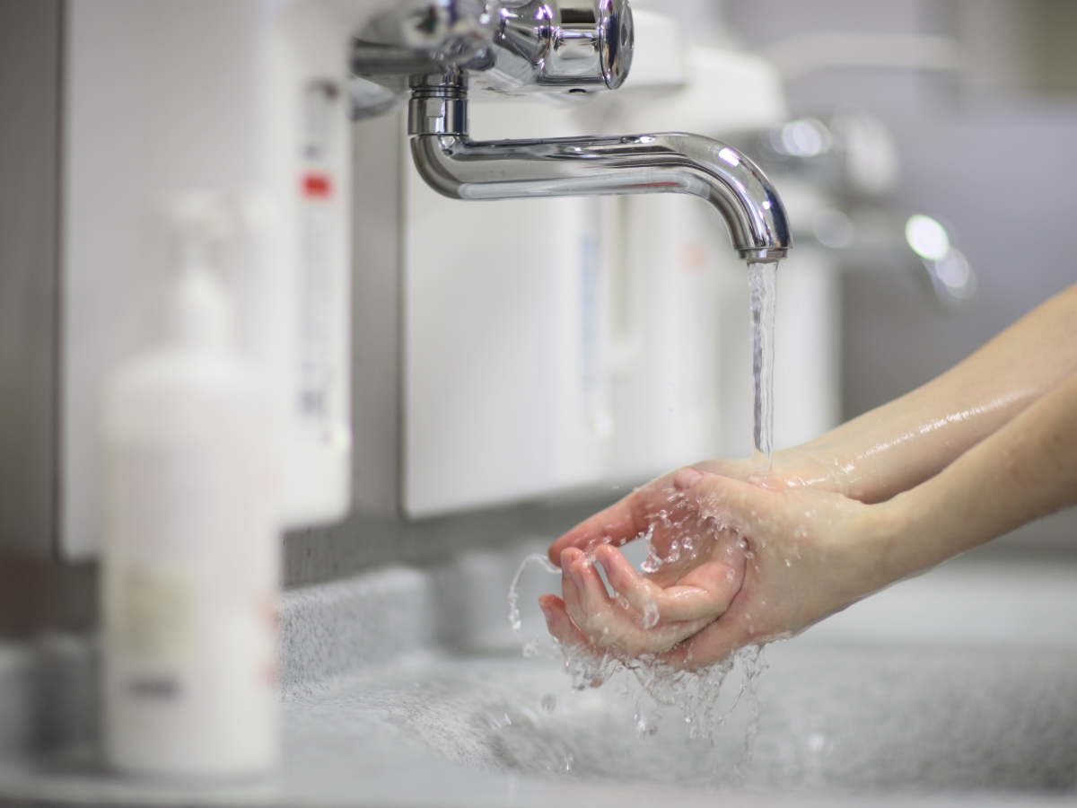 BKK VBU Pflegeportal ambulante Pflegehilfsmittel: Frau desinfiziert ihre Hände unter einem Wasserhahn